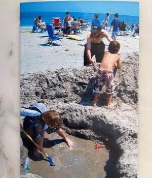David4 David4 is digging a hole in the sand on a beach while another person stands nearby.