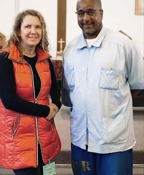Two people in a church A man and a woman standing together inside a church, with a large wooden cross visible in the background.