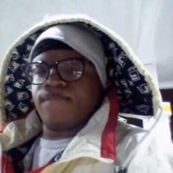 Portrait of Courtney, a person with glasses and a patterned hood, looking directly at the camera.