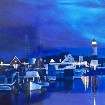 A night scene of a harbor with boats docked, a lit lighthouse, and buildings under a deep blue sky.