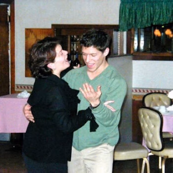 Paul 5 and a woman dancing together in a restaurant setting.