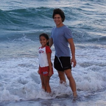 A man and a young girl standing together in the ocean waves.