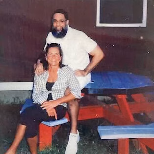 Terence and a woman posing together at a red picnic table.