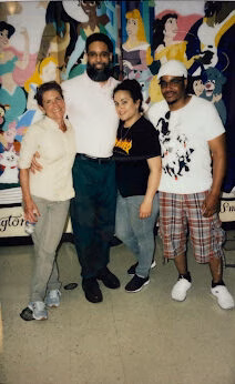 Four people posing for a photo in front of a colorful mural of Disney princesses.