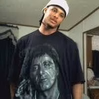 A man wearing a white cap and a black t-shirt featuring a graphic of a woman's face.