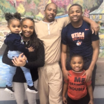 A family of five, including a man, woman, and three children, posing together in front of a mural.
