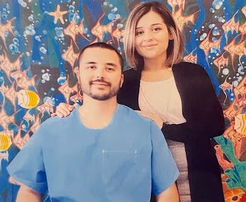Tony and a woman posing in front of a vibrant underwater mural.