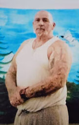 Michael, a bald man with a white tank top, stands in front of a blue and white mural.