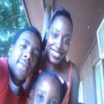 Kyaleah CumminsUnit and her family, a man and a young girl, smiling together on a porch.