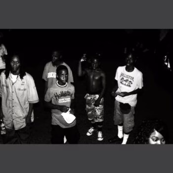 A black and white photograph of a group of young men standing together at night.