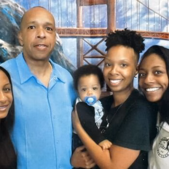 A family of five, including a baby, posing in front of a mural of the Golden Gate Bridge.