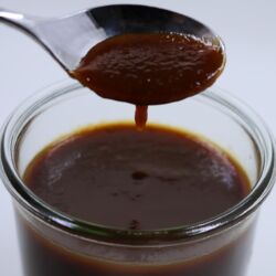 Photo of a spoon dripping barbecue sauce into a jar