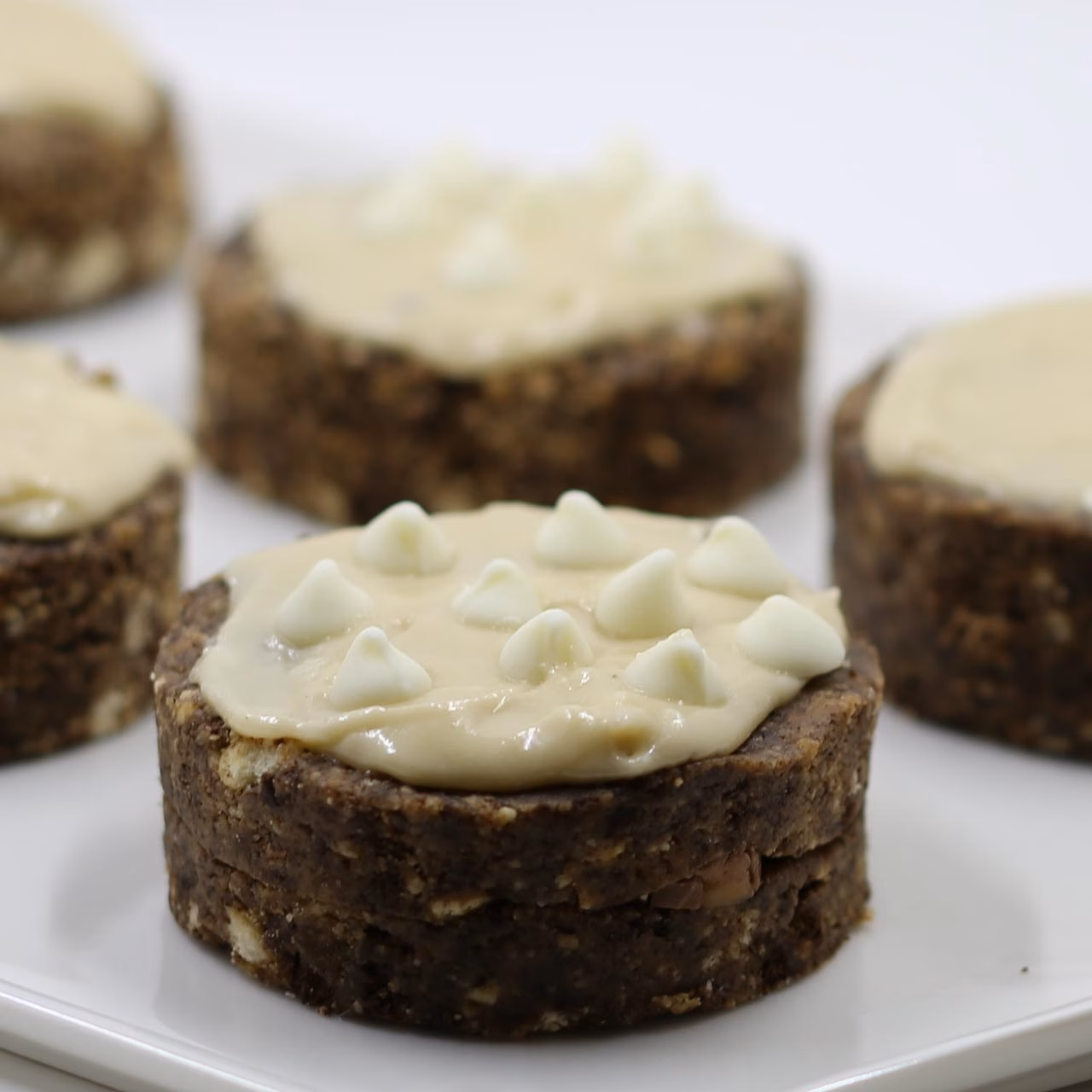 Photo of a dark brown cookie with white frosting and white chocolate chips