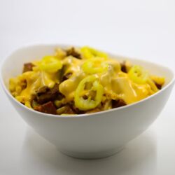 Photo of Mac & Mak in a white bowl and covered with cheese and peppers
