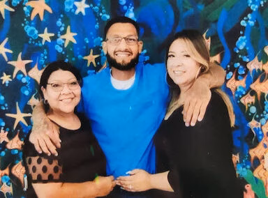Three people posing together in front of a blue starry backdrop.