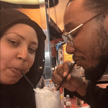 Couple Sharing Milkshake A close-up of a man and a woman sharing a milkshake with straws in a diner.