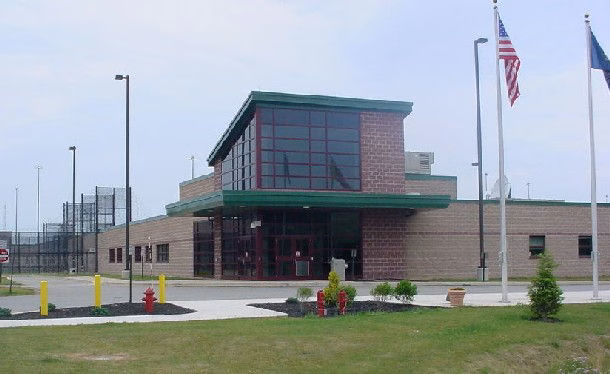 Fayette prison building with brick exterior, large glass entrance, and two flags flying in front.