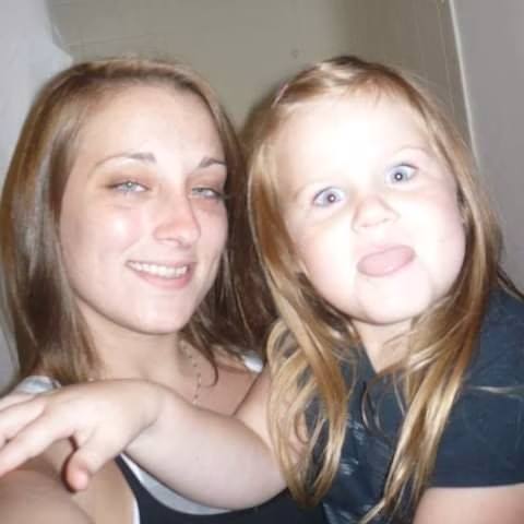 A woman and a young girl with blonde hair pose together for a selfie, both looking directly at the camera.