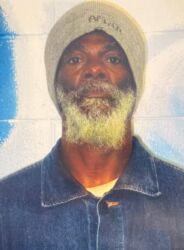 Portrait of Jacob, a man with a long, light-colored beard, wearing a grey beanie with 'AFGHAN' written on it and a blue denim jacket.