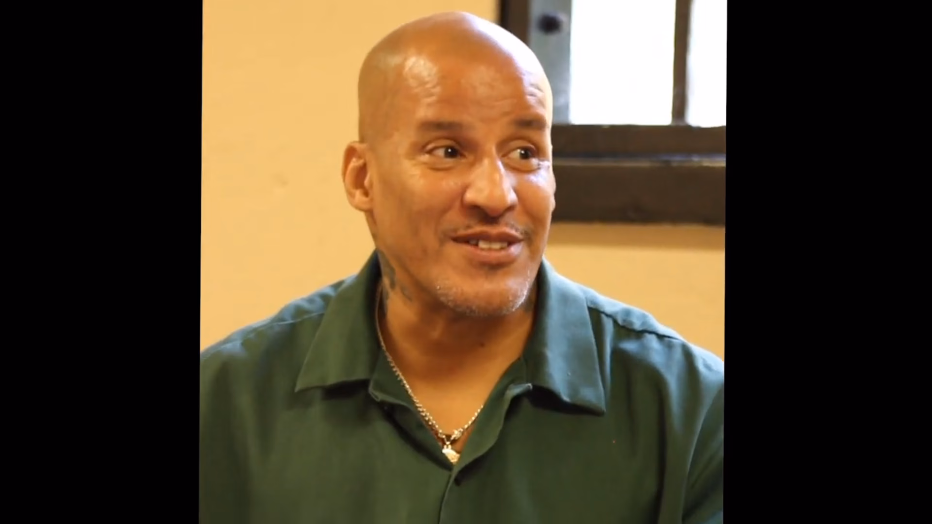 Sammy, 54, a bald man with a goatee and a green shirt, is shown in a close-up during an interview.