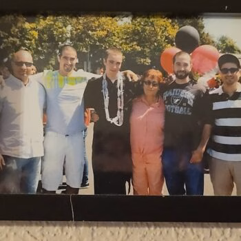 Six people posing for a group photo outdoors with balloons in the background.