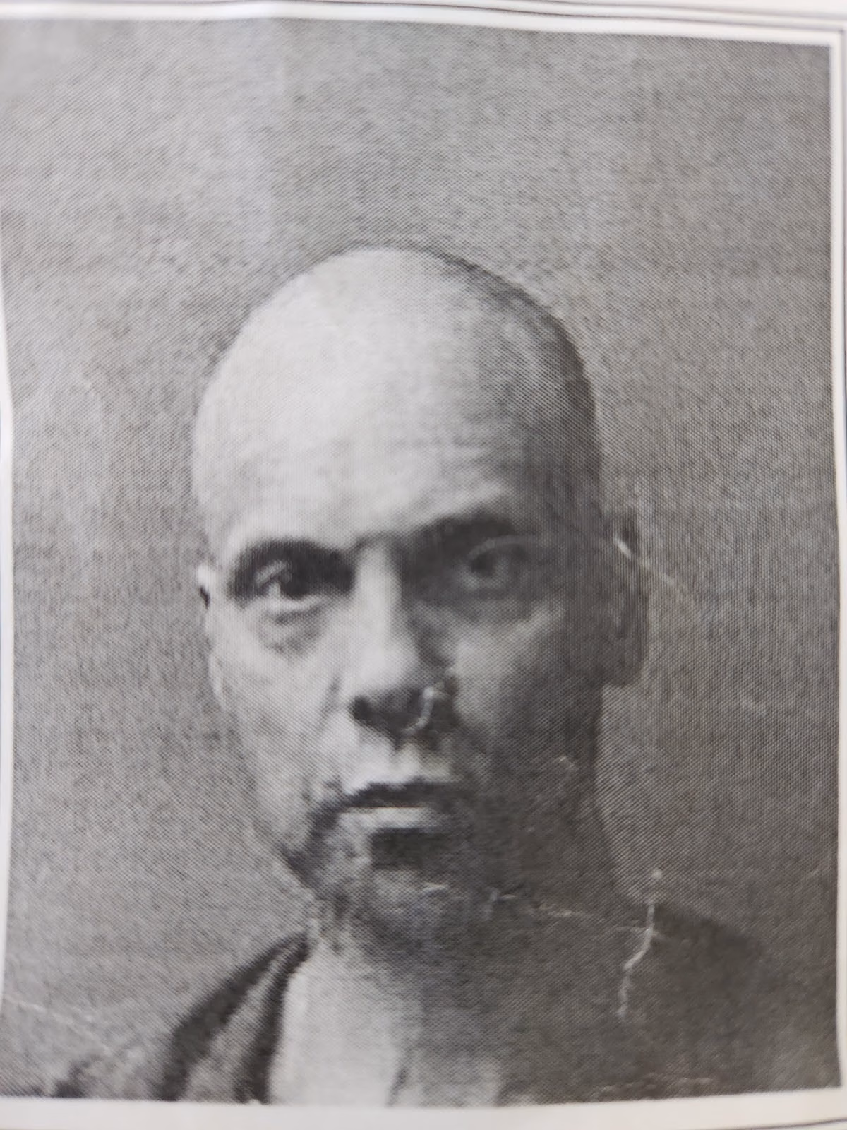 A black and white portrait of a bald man with a serious expression, identified as JAY.