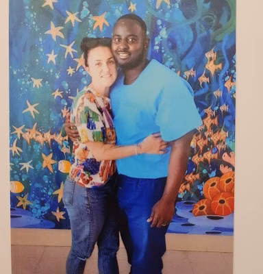 Two people posing together in front of a vibrant mural featuring stars and fish.