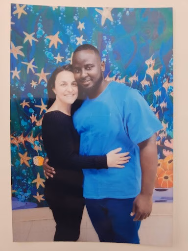 Man and woman at event A man and woman posing together in front of a vibrant, starfish-themed mural.