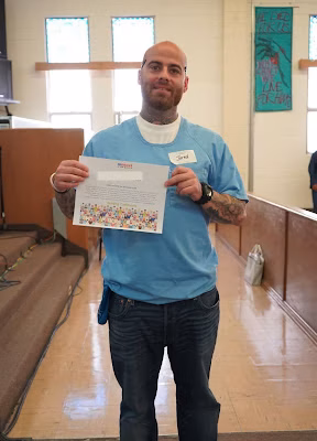 Jared, 40, holds a certificate in a blue shirt inside a church.