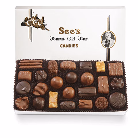 An open box of See's Famous Old Time Candies displaying a variety of assorted chocolates, including truffles, bars, and pralines.