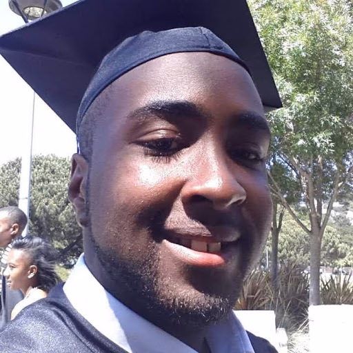 Marcus, 33, smiling in a graduation cap and gown outdoors.