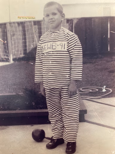 A young boy in a striped 'NEWB-91' uniform stands on a patio with a dumbbell at his feet.