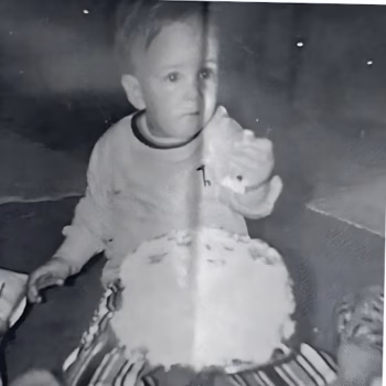 Shane Goddard 3 A young boy in a long-sleeved shirt holds a small object, with a large, textured circular object in the foreground.