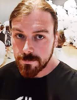 A man with long hair and a beard looking at the camera.