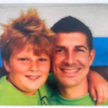 Lucas, 38, and a young boy in green shirts smiling together.