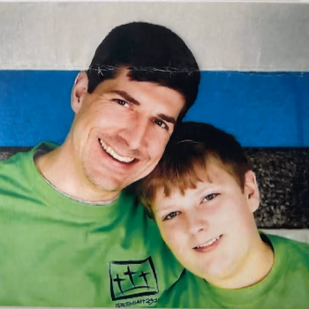 Lucas and a young boy in matching green t-shirts with a Jeremiah 23:21 logo, smiling together.