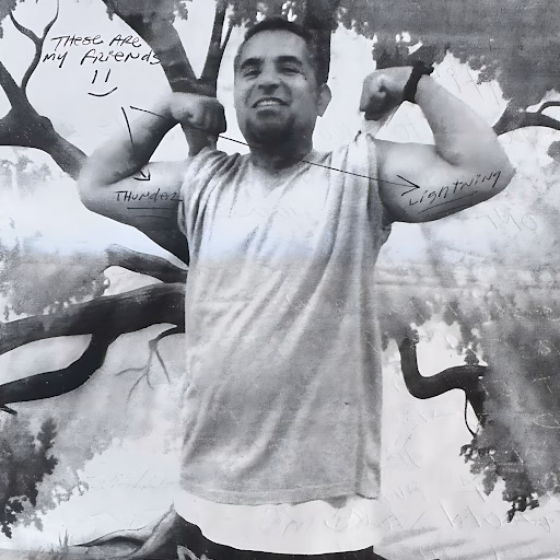 Tony flexing his biceps in a black and white photo with handwritten notes pointing to his arms.