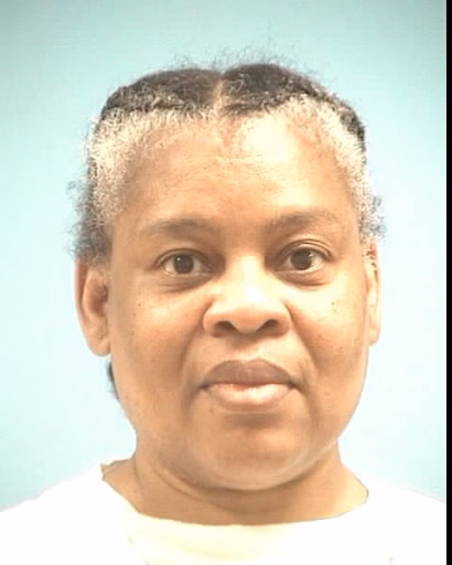 Portrait of Cheryl, 57, a woman with short, graying hair and a white shirt against a light blue background.