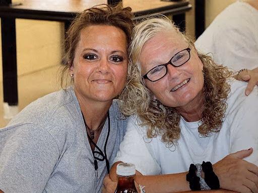 Kim, 38, and a friend share a warm smile together in a casual indoor setting.