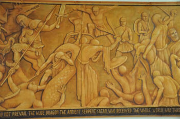 A golden relief mural depicting a battle scene with figures fighting a large dragon, with a caption at the bottom identifying the ancient serpent Satan.