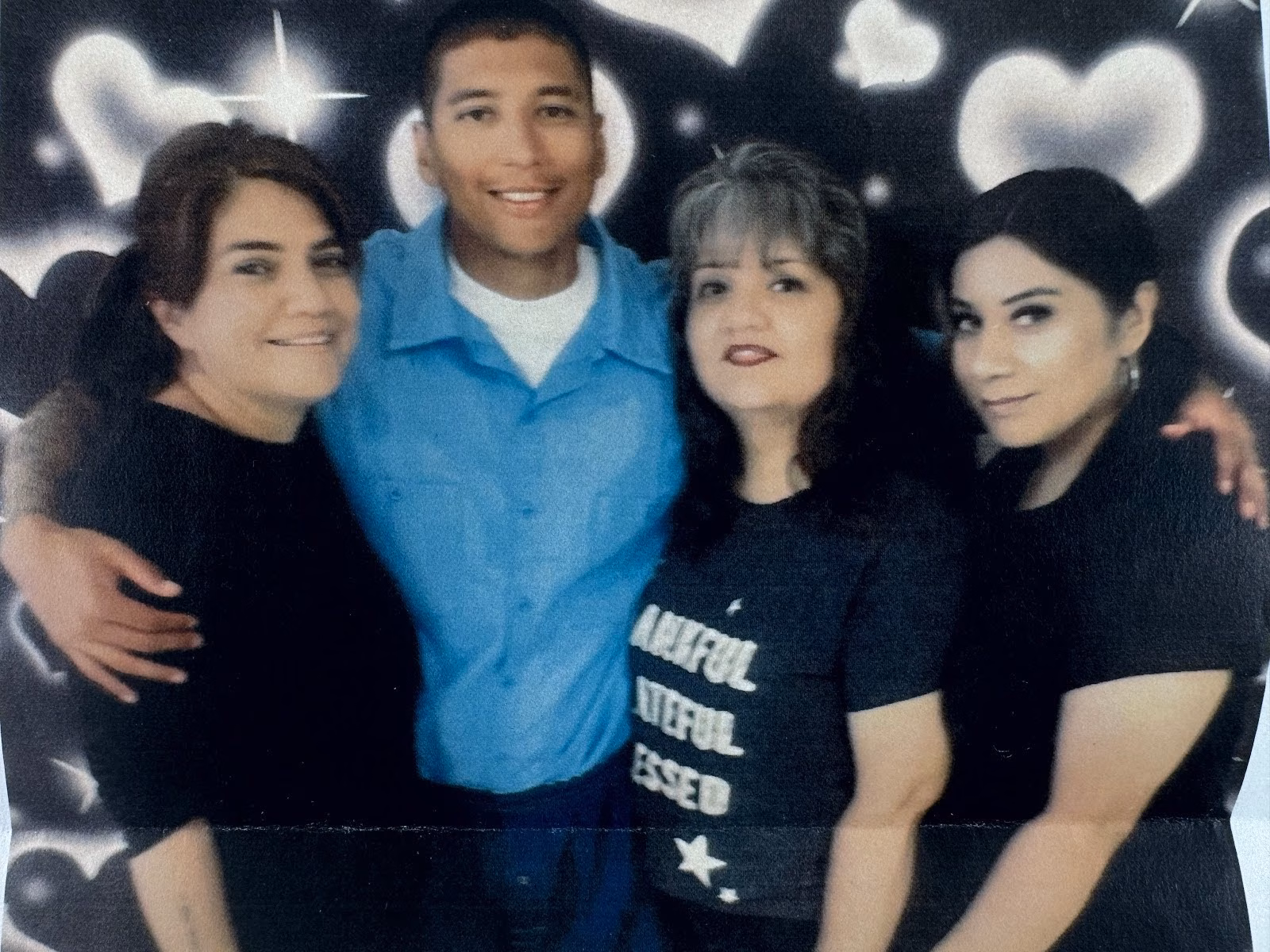 Four people posing together in front of a heart-themed backdrop.