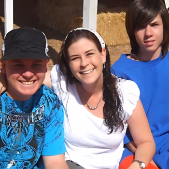 Three people, Casey and two others, smiling together outdoors.