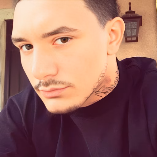 A close-up portrait of Eric, a man with a goatee and a neck tattoo, wearing a black shirt.