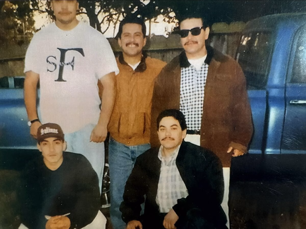 Five men posing for a group photo outdoors in front of a blue truck.