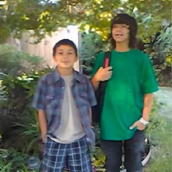 Two young boys, Eric and a friend, standing outdoors in a garden.
