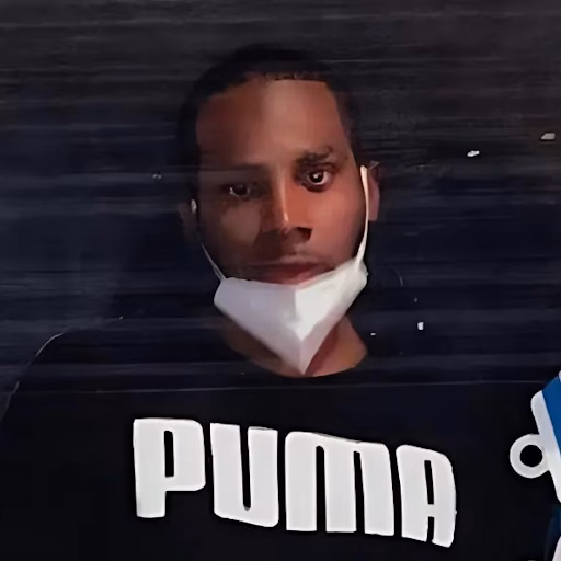 A man named Dejon wearing a Puma shirt and a white face mask pulled down to his chin.
