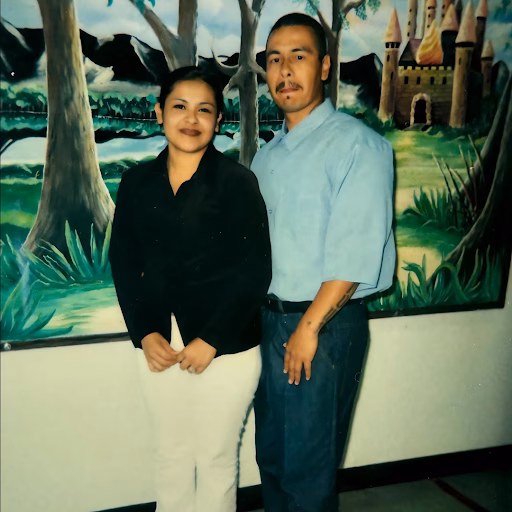 Anthony and a woman stand in front of a fantasy-themed mural featuring a castle and trees.