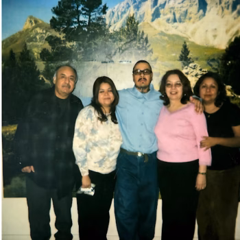 Five people posing together in front of a large mountain landscape mural.