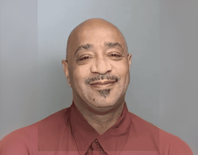 Jeffery, a bald man with a goatee, smiles while wearing a red shirt against a plain background.