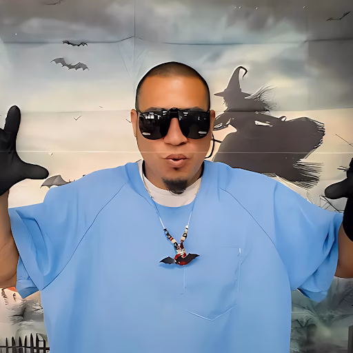 Giovanny wearing sunglasses and a blue shirt, with a witch and bats in the background.